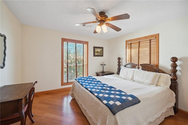 22349 Fm 359th Rd, Hempstead, TX 77445 - bedroom with light wood-style flooring, baseboards, a ceiling fan, and a textured ceiling