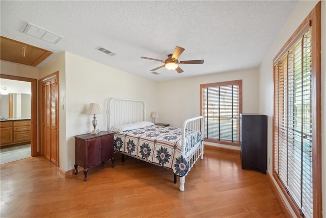 22349 Fm 359th Rd, Hempstead, TX 77445 - bedroom with attic access, light wood-style floors, a textured ceiling, a ceiling fan, and baseboards
