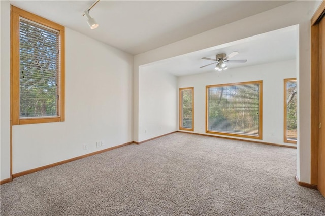 carpeted empty room featuring rail lighting and ceiling fan