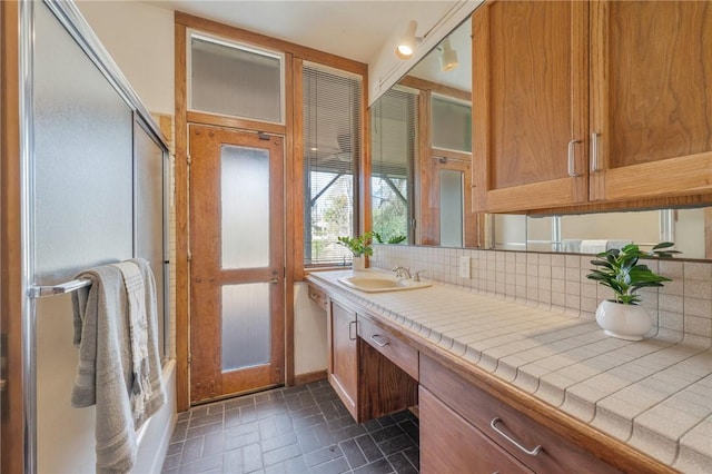 bathroom featuring vanity, backsplash, and shower / bath combination with glass door