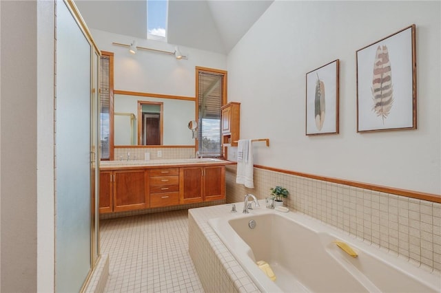 bathroom featuring vaulted ceiling, tiled bath, tile patterned floors, and vanity