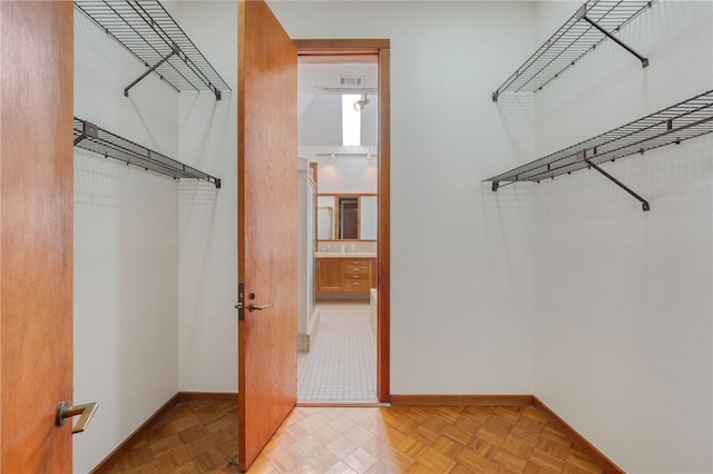 walk in closet with light parquet floors