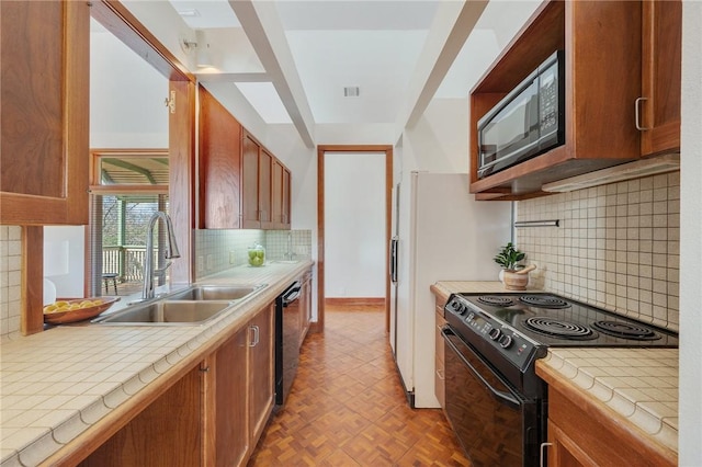 kitchen with sink, light parquet floors, tile counters, black appliances, and decorative backsplash