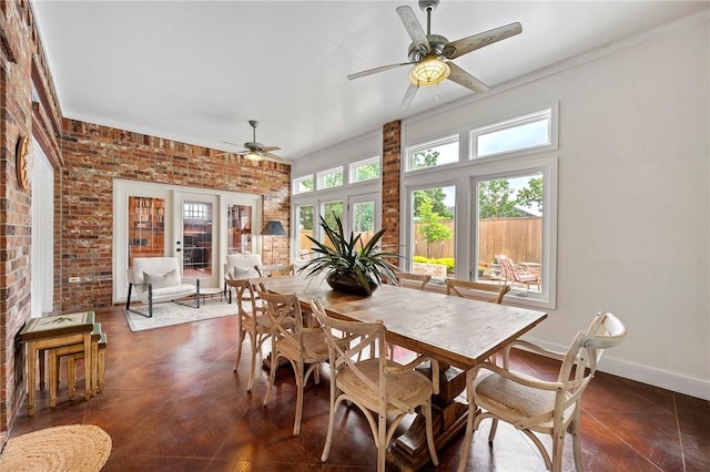 dining space with baseboards, ceiling fan, and brick wall