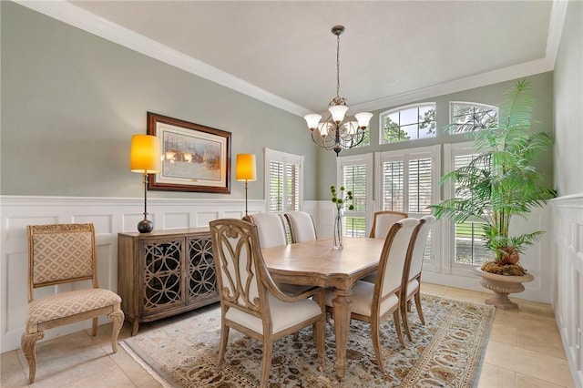 dining room with crown molding, wainscoting, a decorative wall, light tile patterned floors, and a notable chandelier