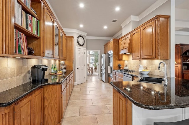 kitchen with a sink, dark stone counters, a peninsula, recessed lighting, and ornamental molding