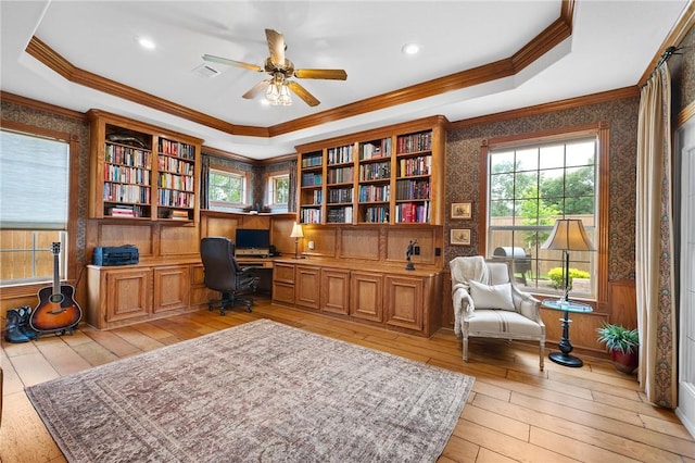 home office featuring crown molding, a healthy amount of sunlight, built in study area, light wood-style floors, and a ceiling fan