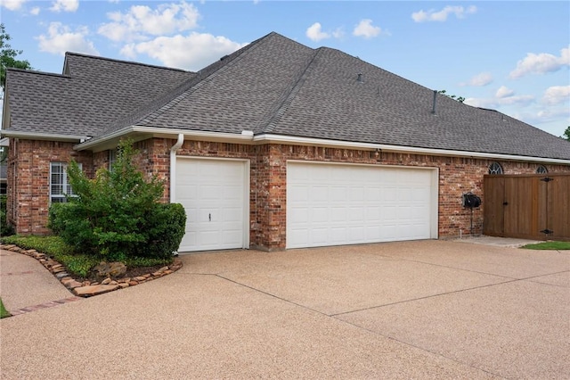 view of property exterior with concrete driveway, brick siding, roof with shingles, and a garage