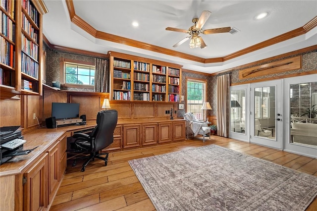 home office with ornamental molding, a tray ceiling, and light wood-type flooring