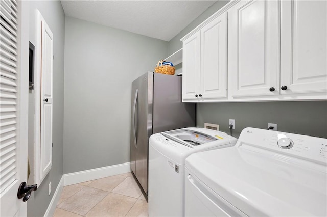 clothes washing area featuring baseboards, light tile patterned flooring, cabinet space, and washer and dryer