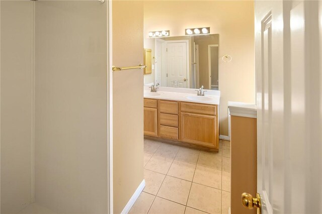 bathroom featuring tile patterned flooring, double vanity, and baseboards