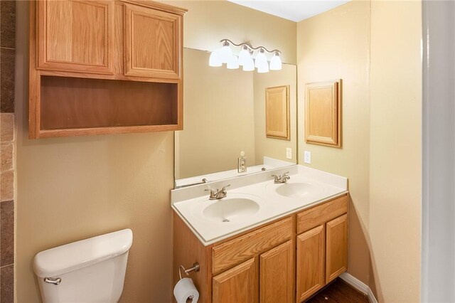 bathroom with toilet and double vanity