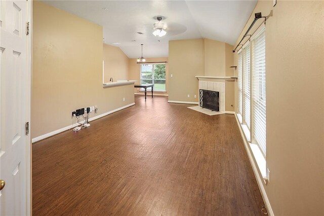 unfurnished living room featuring wood finished floors, vaulted ceiling, a ceiling fan, a fireplace, and baseboards