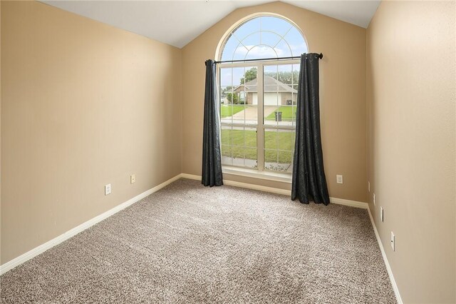 carpeted spare room featuring vaulted ceiling and baseboards