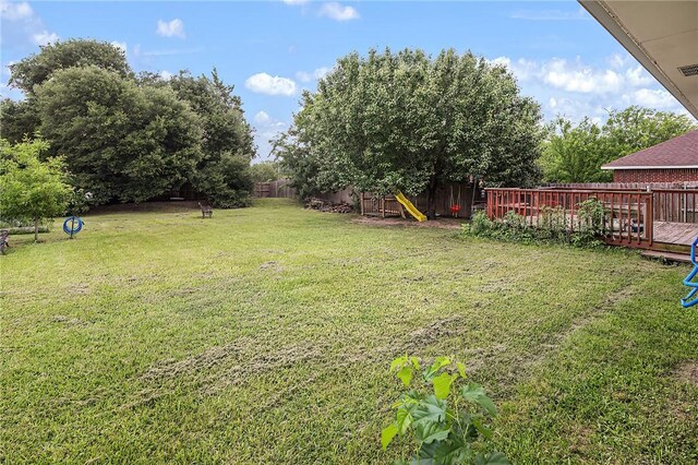 view of yard featuring a deck and a playground