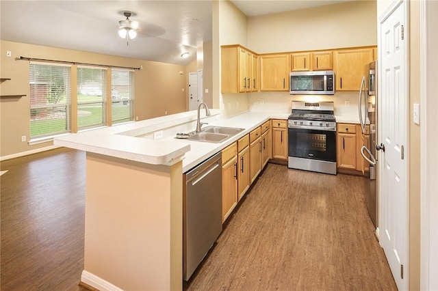 kitchen featuring stainless steel appliances, wood finished floors, a sink, ceiling fan, and lofted ceiling