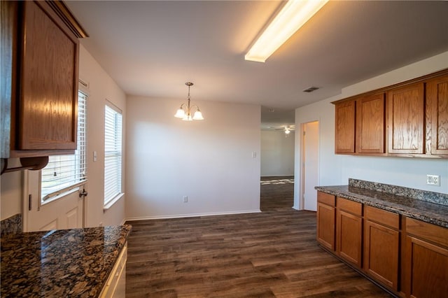 kitchen featuring pendant lighting, dark hardwood / wood-style floors, a notable chandelier, and dark stone countertops