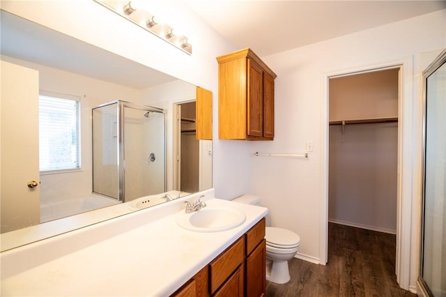 bathroom featuring wood-type flooring, toilet, walk in shower, and vanity