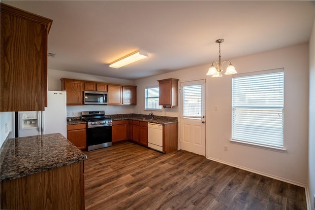 kitchen featuring an inviting chandelier, stainless steel appliances, dark hardwood / wood-style flooring, hanging light fixtures, and dark stone counters