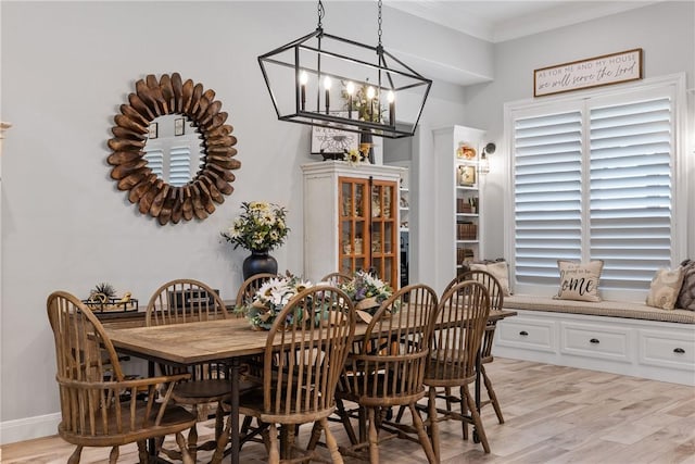 dining space featuring crown molding, light hardwood / wood-style floors, and an inviting chandelier