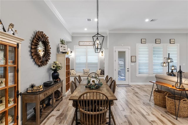 dining room featuring a chandelier, crown molding, and light hardwood / wood-style flooring