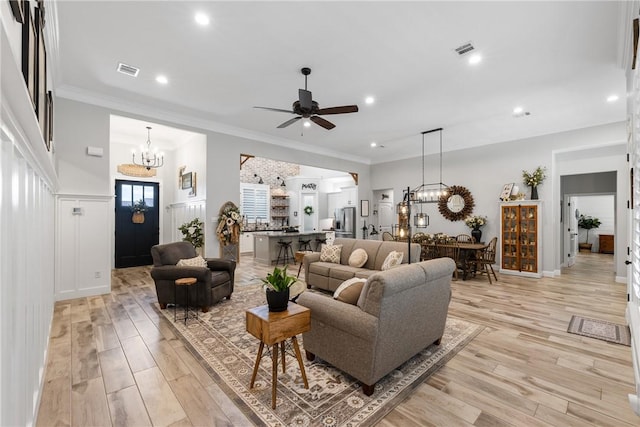 living room featuring sink, ornamental molding, ceiling fan with notable chandelier, and light wood-type flooring