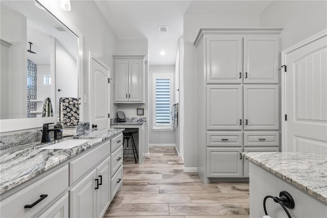 kitchen featuring white cabinetry, sink, light stone countertops, and light hardwood / wood-style flooring