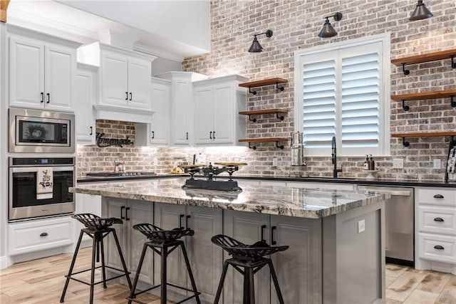 kitchen with dark stone counters, white cabinetry, a center island, and stainless steel appliances