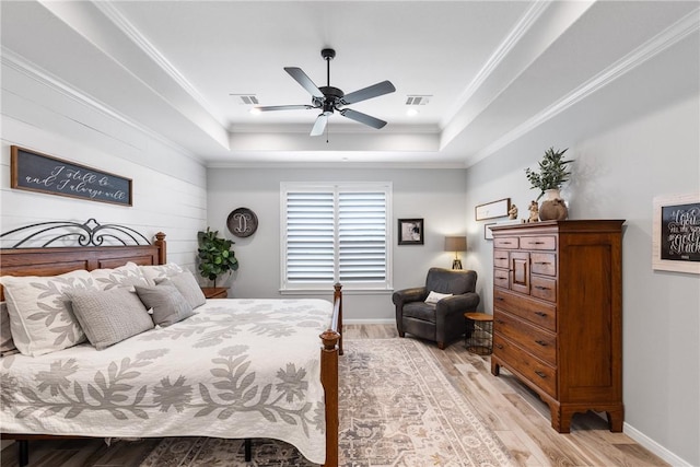 bedroom with a tray ceiling, ceiling fan, light hardwood / wood-style floors, and ornamental molding