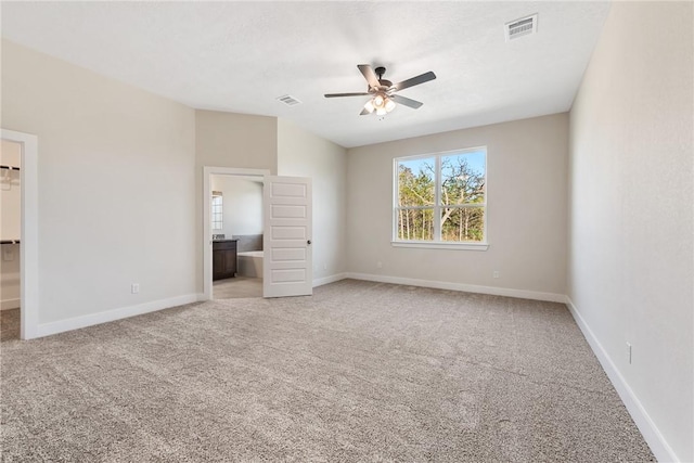 unfurnished bedroom featuring ceiling fan, light colored carpet, a spacious closet, and connected bathroom