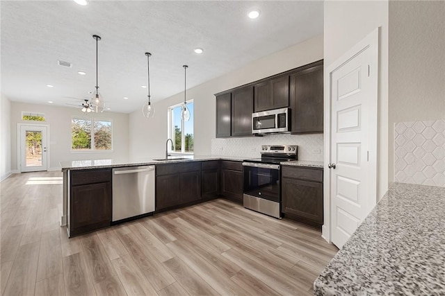 kitchen featuring kitchen peninsula, sink, decorative light fixtures, and appliances with stainless steel finishes