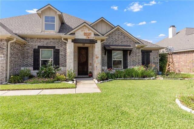 4004 Wild Creek Ct, College Station, TX 77845 - french country home with a front yard, a shingled roof, stone siding, and brick siding