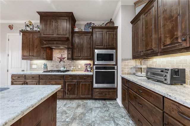 4004 Wild Creek Ct, College Station, TX 77845 - kitchen with appliances with stainless steel finishes, crown molding, tasteful backsplash, light stone counters, and dark brown cabinetry