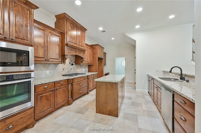 kitchen with sink, appliances with stainless steel finishes, tasteful backsplash, a kitchen island, and light stone counters