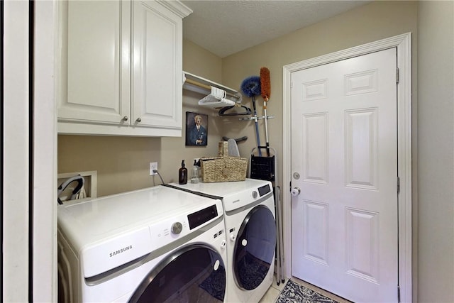 washroom with cabinets, washing machine and dryer, and a textured ceiling