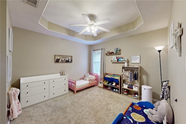 bedroom featuring a tray ceiling, ceiling fan, and light colored carpet