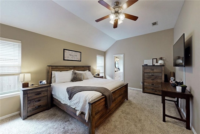 carpeted bedroom featuring ceiling fan, lofted ceiling, ensuite bathroom, and multiple windows