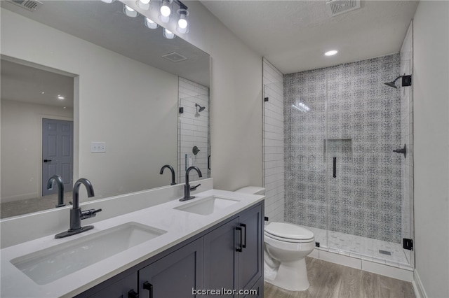 bathroom with hardwood / wood-style floors, vanity, toilet, and an enclosed shower