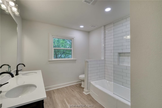 full bathroom featuring vanity, hardwood / wood-style flooring, toilet, and tiled shower / bath combo