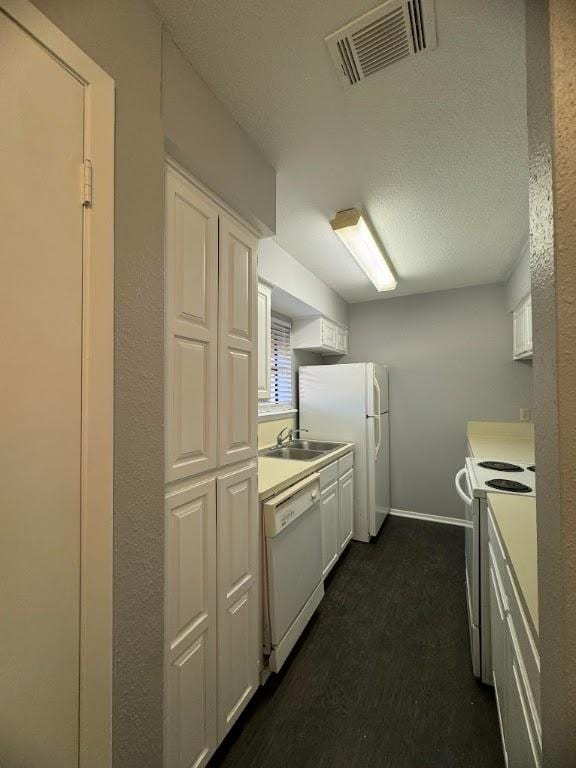 kitchen with light countertops, visible vents, white cabinets, white appliances, and baseboards