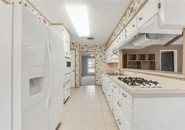 2100 Langford St, College Station, TX 77840 - kitchen with white appliances, wallpapered walls, white cabinets, light countertops, and light tile patterned flooring