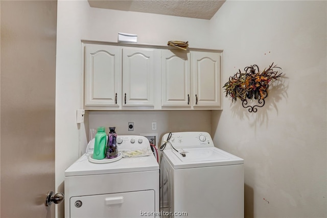 laundry room featuring washer and clothes dryer, cabinets, and a textured ceiling