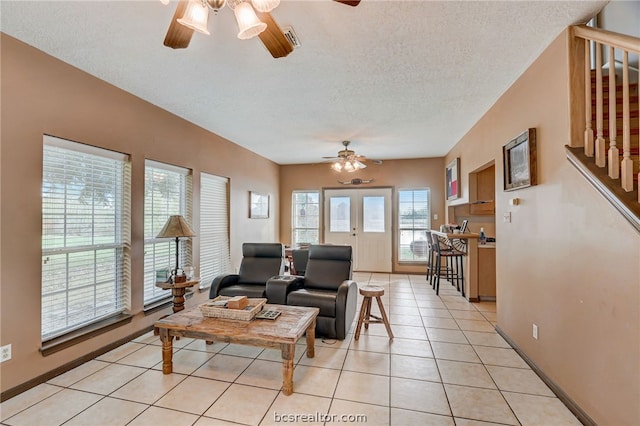 tiled living room featuring french doors, a textured ceiling, and ceiling fan