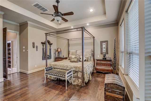 bedroom with a raised ceiling, ceiling fan, crown molding, and dark wood-type flooring