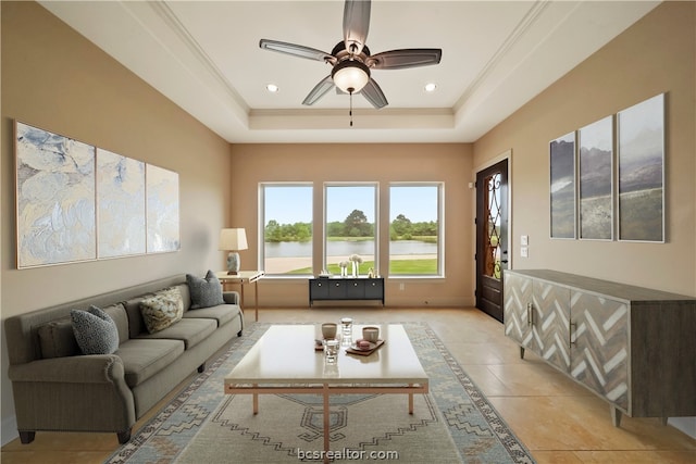 tiled living room featuring a water view, a raised ceiling, ceiling fan, and crown molding