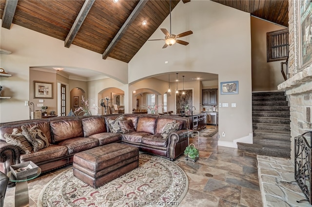 living room featuring high vaulted ceiling, ceiling fan, wooden ceiling, and a stone fireplace