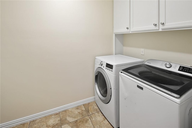 clothes washing area featuring cabinets, washer and clothes dryer, and light tile patterned flooring