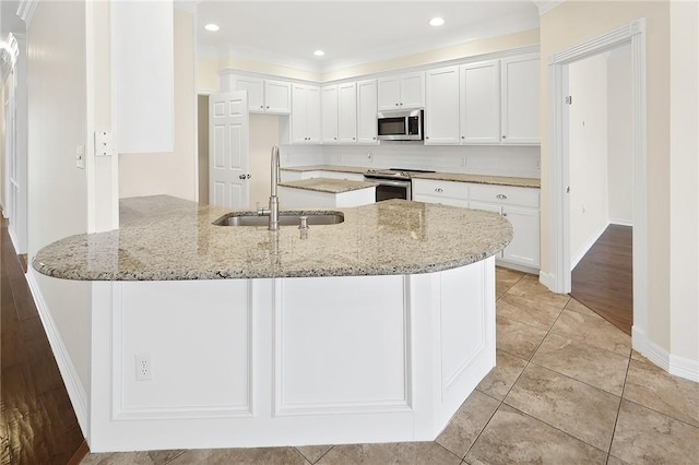 kitchen with sink, stainless steel appliances, white cabinets, and light stone counters