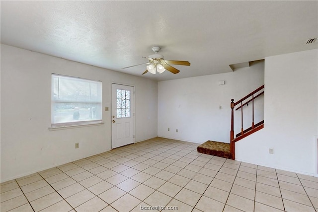 interior space featuring ceiling fan, light tile patterned floors, and a textured ceiling