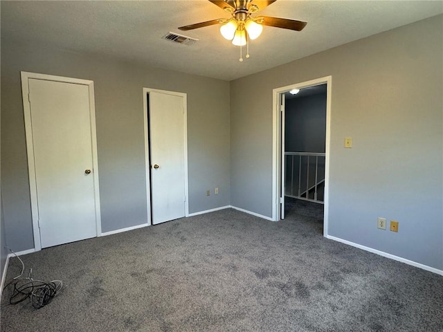 unfurnished bedroom with dark colored carpet and ceiling fan